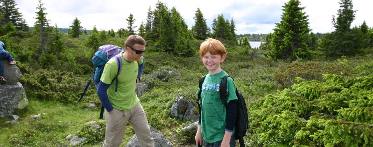 en person og et barn med ryggsekker på en steinete sti
