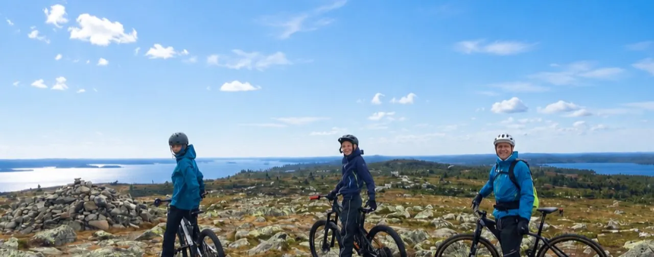3 personer som sykler på toppen av fjellet