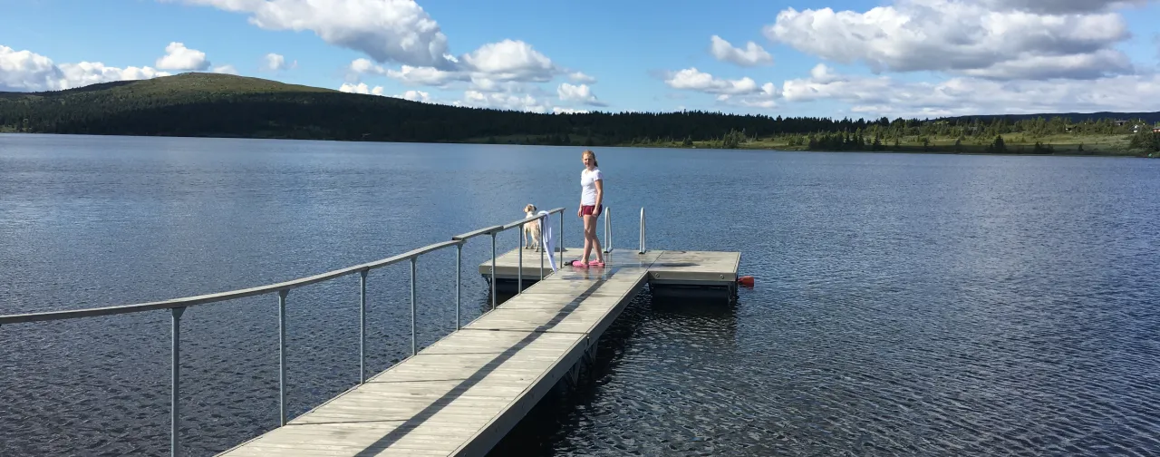 en person og et barn på en brygge over en innsjø