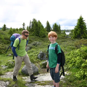 en person og et barn med ryggsekker på en steinete sti