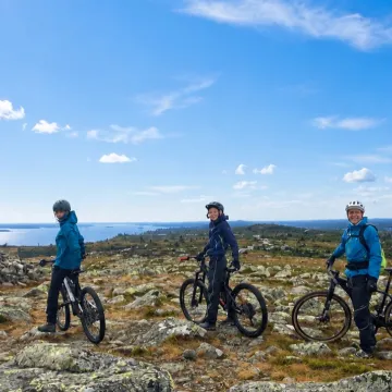 3 personer som sykler på toppen av fjellet